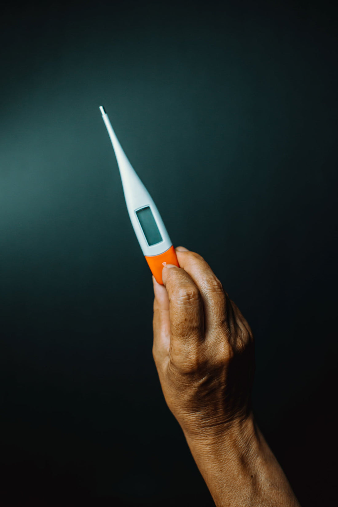 Image of a hand holding a thermometer 