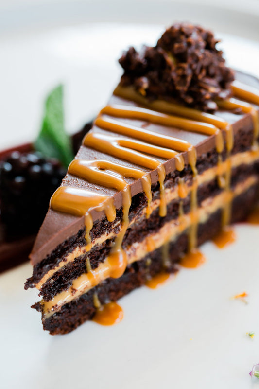 Image of a slice of layered chocolate cake with caramel sauce drizzled on top
