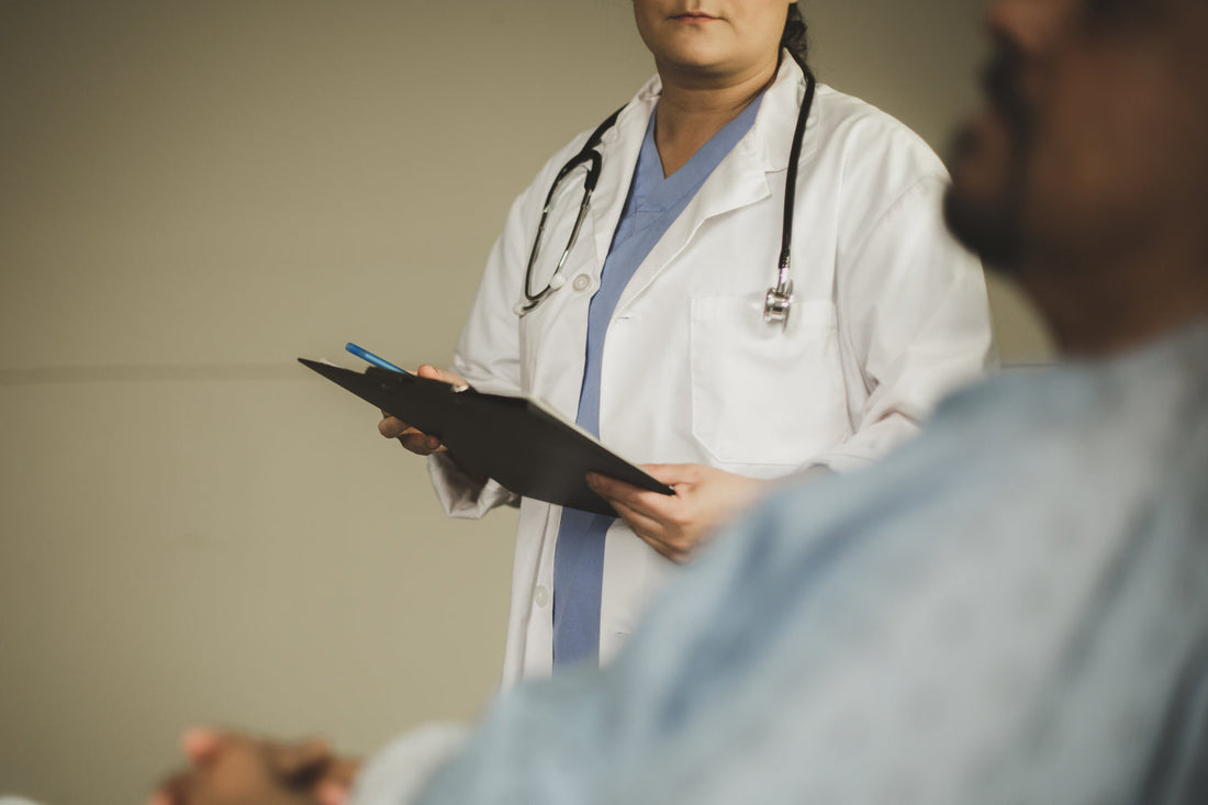 Image of doctor holding clipboard in front of patient wearing a medical gown