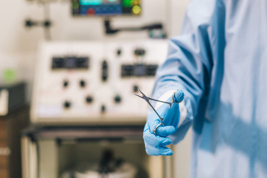Image of a surgeon wearing medical gown and gloves holding a surgical instrument