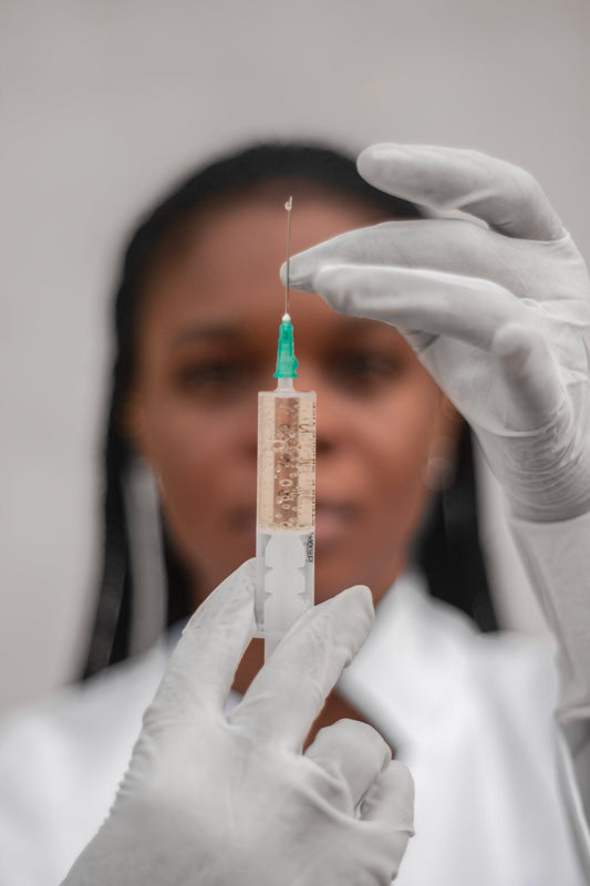 Image of female physician wearing medical gloves holding syringe with medicine