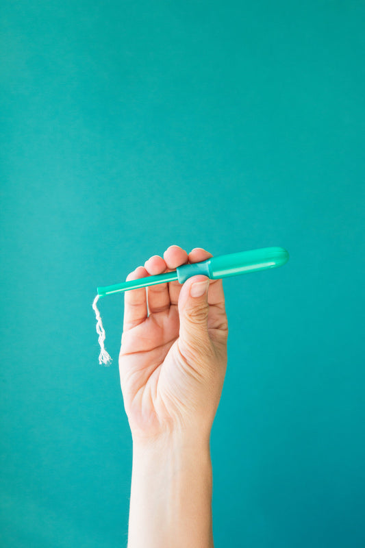 Image of a hand holding a blue/green tampon